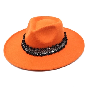 Détail chapeau fedora orange à large bord avec ruban en tweed noir et blanc