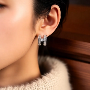 Close-up of silver letter H ear cuff with cubic zirconia worn by a model in soft light