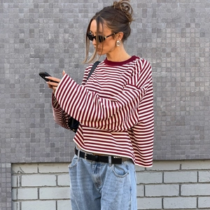Street style shot of burgundy striped long sleeve top with crew neck and casual fit