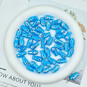 Macro shot of blue ceramic fish beads for DIY jewelry making in a decorative tray