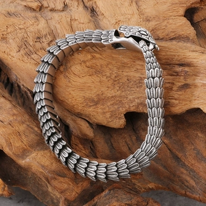 Macro shot of antique silver snake bracelet with bionic scales on a rustic wood base