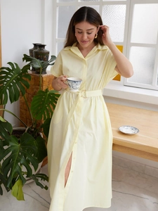 Detail of light yellow cotton shirt dress featuring button-down front and belted waist