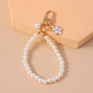 Close-up of pearl bead keychain with golden lobster clasp and white enamel flower