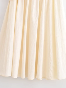 Detailed macro view of the cream pleated fabric texture and vertical fold design on the skirt