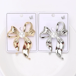 Detail of gold and silver bow brooches with pearls on a white display card
