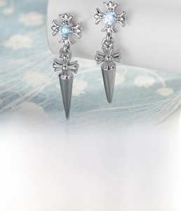 Detail von silbernen Kreuz-Ohrsteckern mit hellblauem Zirkon und Kegel-Anhängern