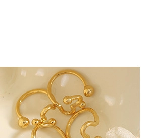 Nahaufnahme eleganter goldener Wellen-Ohrringe auf Keramik mit weißen Blütenblättern