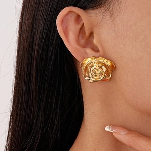 Gros plan d'une grande boucle d'oreille rose dorée 3D avec pétales en métal poli sur modèle
