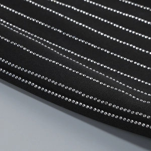 Close-up of black fabric featuring rows of sparkling silver rhinestones on a party dress
