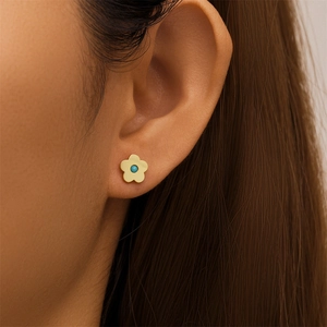 Detailed view of silver flower stud earring with turquoise center on model's ear