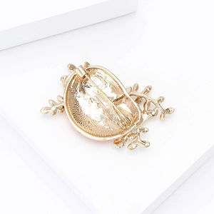 Detailed view of the gold alloy brooch with a secure safety pin clasp on white stand