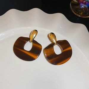 Detailed view of vintage amber resin hoop earrings with gold alloy on white ceramic tray