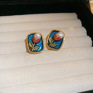 Macro view of gold plated tulip flower earrings with pearls on white velvet box