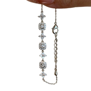 Hand holding an 18K gold plated adjustable bracelet with zircon flowers and square charms