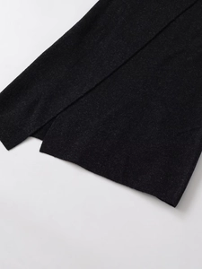 Detailed close-up showing the side slit design and knit texture of a black midi skirt