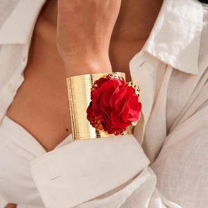Detail of bohemian gold open bangle with bold red fabric flower on linen shirt