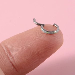 Detail eines G23 Titan Nasenrings mit weißem Opal-Inlay, auf dem Finger gehalten
