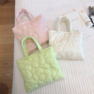 Dettaglio della trama floreale trapuntata su mini borse imbottite in rosa bianco e verde