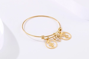 Detail of adjustable gold bangle with boy, girl, and Mom heart charms on white background