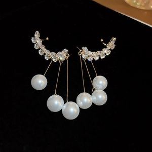 Close-up of gold leaf drop earrings with sparkling rhinestones and white pearls on velvet