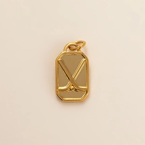 Detailed close-up of a 18k gold plated rectangular pendant with embossed hockey sticks