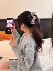 Detail of light purple chiffon bow hair clip with flowing ribbons on a model ponytail