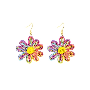 Détail macro de boucles d'oreilles marguerites tressées avec pétales en raphia multicolores