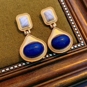 Detail of vintage resin earrings with purple stones on olive textured fabric