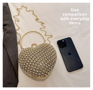 Size comparison of heart-shaped rhinestone clutch with gold handle and phone