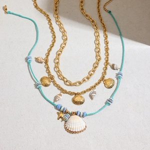 Detail of layered gold necklace with turquoise rope, white seashell, and starfish charms