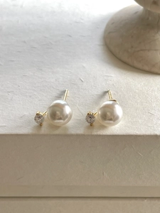 Detail of 925 sterling silver gold stud earrings with white pearls and zircon accents