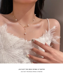 Detail of elegant gold Y-shaped pearl necklace on collarbone with minimalist style