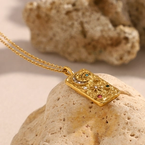 Detail of 18K gold plated celestial pendant with hammer texture and colorful gemstones