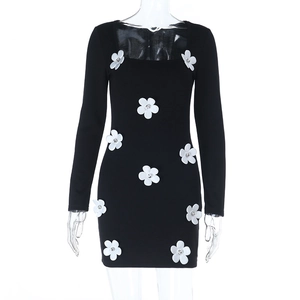 Détail de fleurs 3D blanches avec strass sur une robe noire ajustée à manches longues