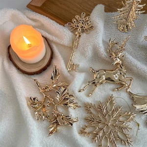 Golden Christmas ornaments set with reindeer, snowflakes and trees on white plush fabric