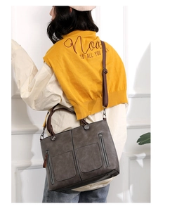 Detail of dark grey PU leather tote bag with dual front pockets and brown shoulder straps