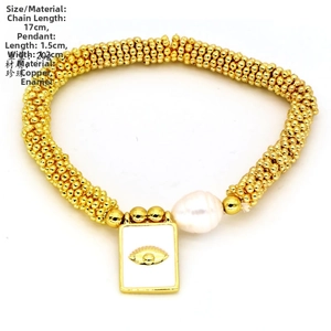 Detail of bohemian gold bead bracelet with white baroque pearl and evil eye charm