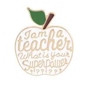 Detail of apple shaped teacher brooch with golden letters on white enamel background