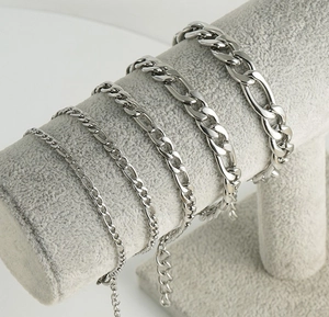 Various thickness silver stainless steel Figaro and curb link chains on a velvet display