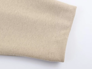 Detail view showing smooth knit fabric texture and high-quality stitching on beige tracksuit