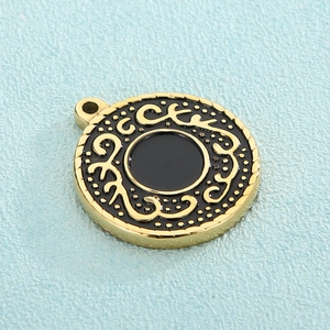 Golden round titanium steel pendant featuring black enamel swirl patterns and dot textures