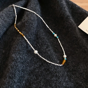 Detail of beaded necklace with silver metal beads, pearls and tiger eye stone