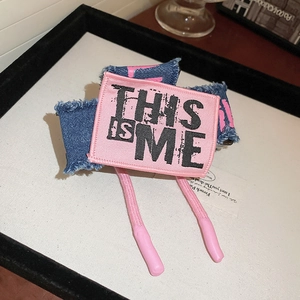 Close-up of pink and denim blue fabric bow hair claw with frayed edges and embroidery