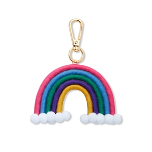 Detailed macro view of a colorful handmade macrame rainbow charm with soft white pom poms