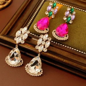 Detailed view of vintage diamond-set teardrop earrings on a luxury green velvet cushion