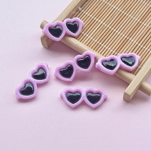 Macro shot of small pink heart-shaped resin sunglasses accessories on a bamboo tray
