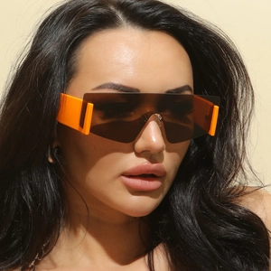 Detail of fashion oversized wrap-around sunglasses with orange temples and tinted lens