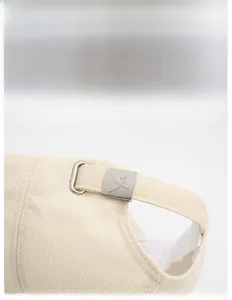 Close-up of the adjustable metal buckle and beige textured fabric on the baseball cap