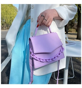 Fashionable purple leather handbag with matching thick chain detail on white blazer outfit