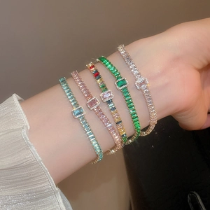 Dettaglio ravvicinato di bracciali tennis impilati con zirconi colorati a taglio quadrato